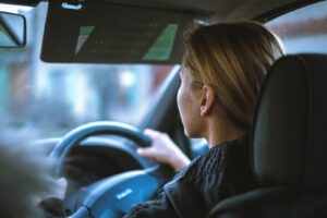 a woman sitting in a car with a steering wheel