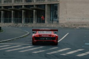 A red sports car driving down a city street