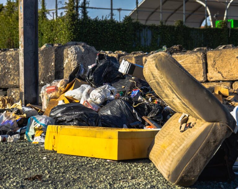 Outdoor scene of a garbage pile including a discarded mattress and various waste materials.