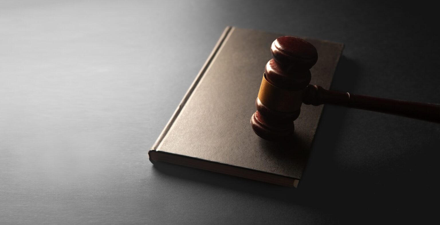 A wooden gavel rests on a closed book.