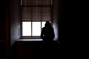 a person standing in front of a window in a dark room
